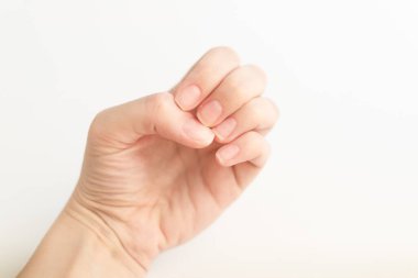 Yumuşak kare şeklinde tırnakları olan kadın eli parmaklarında bir şey tutuyor. Kadın sanal nesneyi saklar. Evde çivi bakımı. Boşluğu kopyala