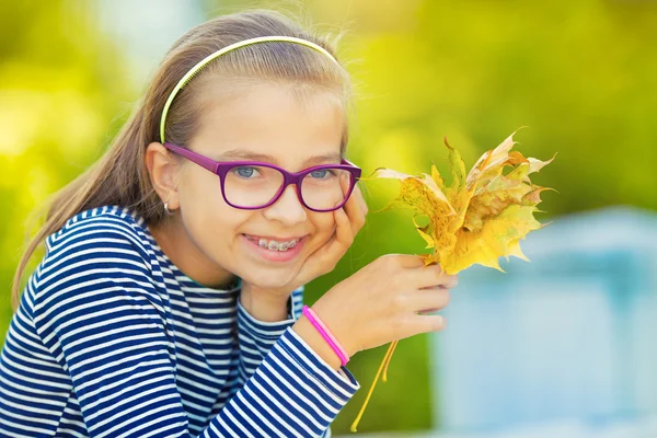 Autumn. Portrait of a smiling young girl who is holding in her hand a bouquet of autumn maple leaves