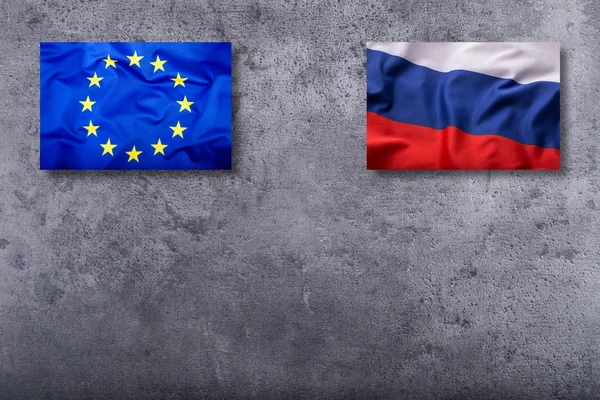 Banderas de Rusia y de la Unión Europea sobre fondo concreto — Foto de Stock