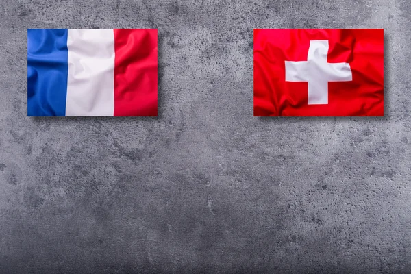 Příznaky z Francie a Švýcarska na konkrétní pozadí — Stock fotografie
