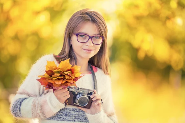 Hora do Outono. A jovem atraente adolescente bonito com buquê de outono e câmera retro. Jovem fotógrafo outono temporada — Fotografia de Stock