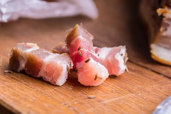 Rå rökt bacon skivor på träskiva med spiskummin och örter — Stockfoto