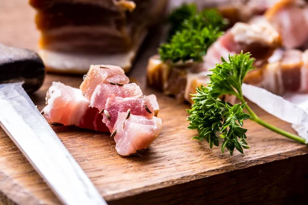 Raw smoked bacon slices on wooden board with cumin and herbs — Stock Photo, Image