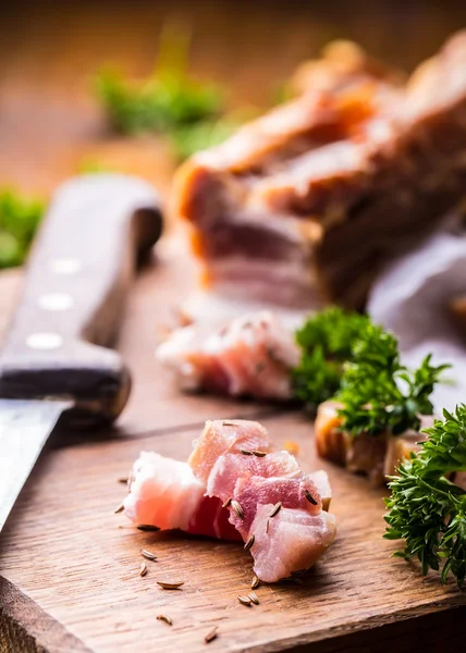 Rauw gerookt spek segmenten op een houten bord met komijn en kruiden — Stockfoto