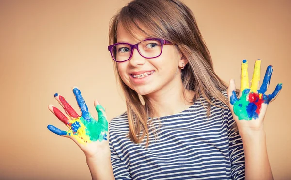 Retrato de uma menina estudante pré-adolescente mostrando as mãos pintadas. Foto tonificada — Fotografia de Stock