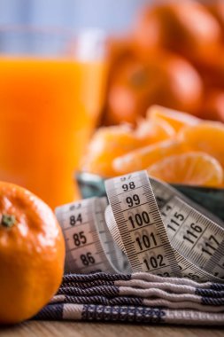 Taze tropikal meyve ve ölçü birimi bant. Mandalina, soyulmuş mandalina ve mavi bir bez mandalina dilimleri. Mandarine suyu