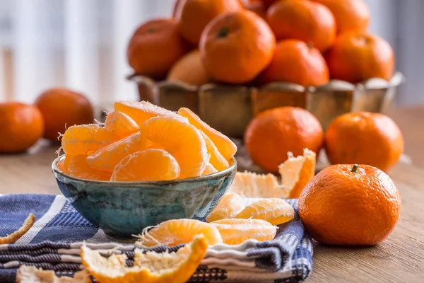 Tangerinas, tangerina descascada e fatias de tangerina em um pano azul. Sumo de mandarina — Fotografia de Stock