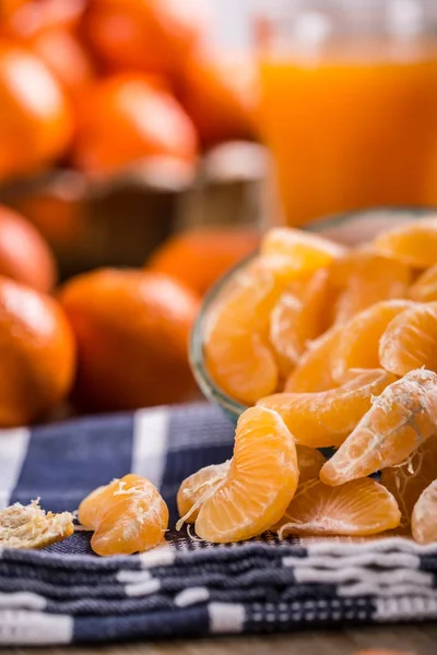 Tangerinas, tangerina descascada e fatias de tangerina em um pano azul. Sumo de mandarina — Fotografia de Stock