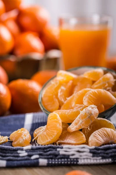 Tangerinas, tangerina descascada e fatias de tangerina em um pano azul. Sumo de mandarina — Fotografia de Stock