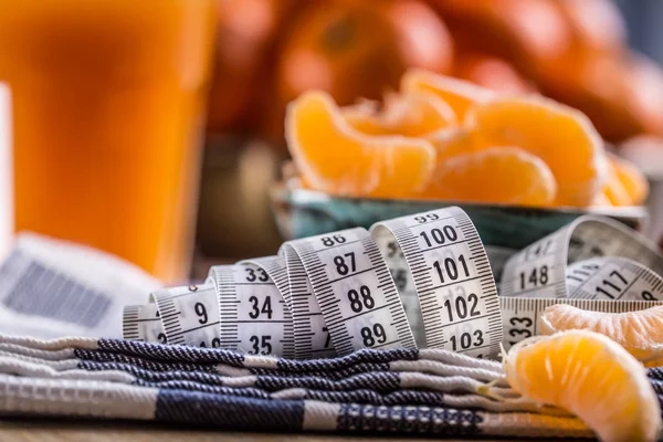 Frutas tropicais frescas e fitas de medida. Tangerinas, tangerina descascada e fatias de tangerina em um pano azul. Sumo de mandarina — Fotografia de Stock