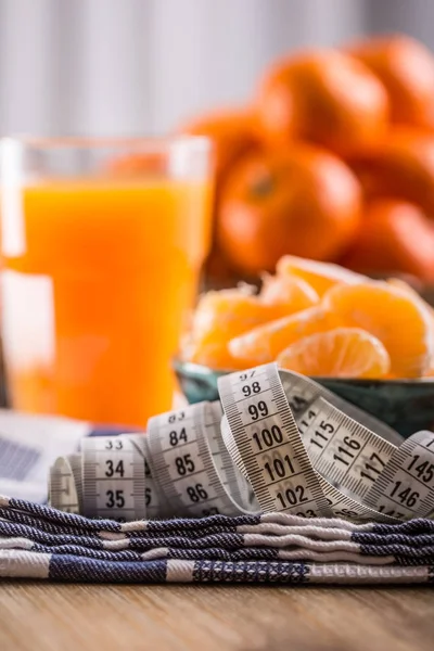 Frutas tropicais frescas e fitas de medida. Tangerinas, tangerina descascada e fatias de tangerina em um pano azul. Sumo de mandarina — Fotografia de Stock