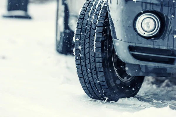 Primer plano de los neumáticos del coche en una carretera nevada.Blizzard en la carretera —  Fotos de Stock