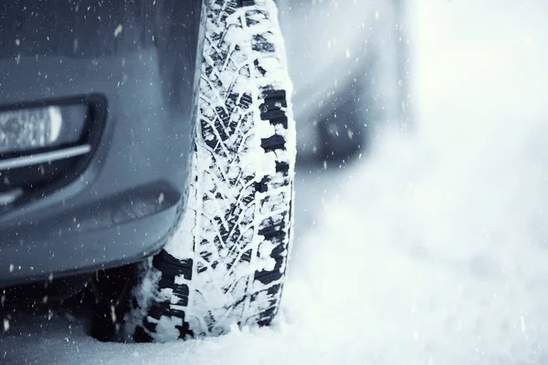 Primer plano de los neumáticos del coche en una carretera nevada.Blizzard en la carretera —  Fotos de Stock