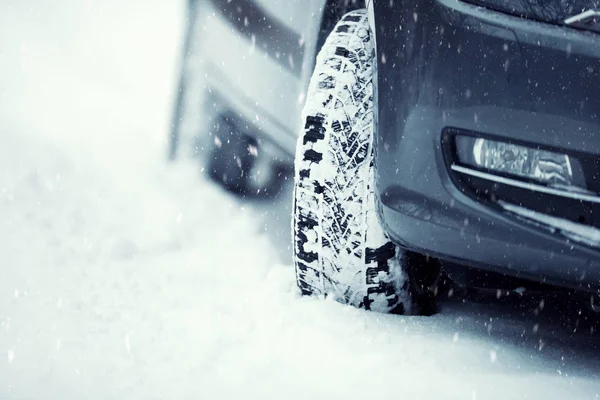 Primer plano de los neumáticos del coche en una carretera nevada.Blizzard en la carretera —  Fotos de Stock