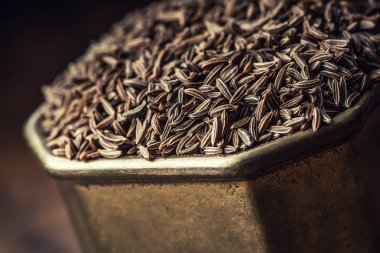 Cumin.Caraway tohumlar ahşap masa üzerinde. Vintage bronz kase ve kaşığı kimyon