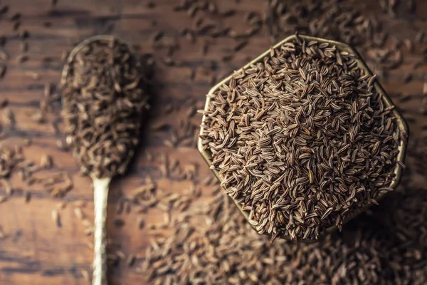 Cumin.Caraway magokat a fából készült asztal. Római kömény vintage bronz tál és kanál — Stock Fotó