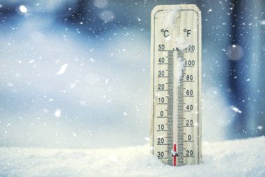 Thermometer on snow shows low temperatures under zero. Low temperatures in degrees Celsius and fahrenheit. Cold winter weather twenty under zero clipart