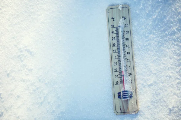 El termómetro en la nieve muestra temperaturas bajas bajo cero. Temperaturas bajas en grados Celsius y fahrenheit. Clima frío de invierno veinte bajo cero —  Fotos de Stock