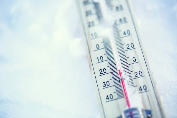 El termómetro en la nieve muestra temperaturas bajas bajo cero. Temperaturas bajas en grados Celsius y fahrenheit. Clima frío de invierno veinte bajo cero — Foto de Stock