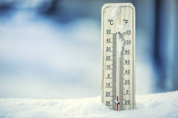Thermometer on snow shows low temperatures under zero. Low temperatures in degrees Celsius and fahrenheit. Cold winter weather twenty under zero