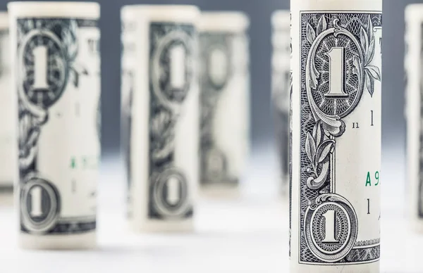 Доллар. Банкноты в долларах скручиваются в других позициях. Американская валюта на белой доске и разряженный фон — стоковое фото