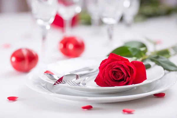 Ρύθμιση του πίνακα για του Αγίου Βαλεντίνου ή την ημέρα του γάμου με κόκκινα τριαντάφυλλα. Ρύθμιση ρομαντικό τραπέζι για δύο με τριαντάφυλλα πιάτα, ποτήρια και μαχαιροπίρουνα — Φωτογραφία Αρχείου