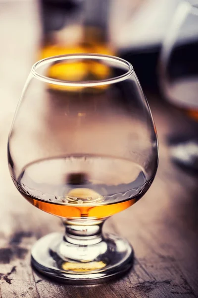 Glas whiskey cognac brandy of rum. De helft volle glazen cognac op een houten ondergrond — Stockfoto