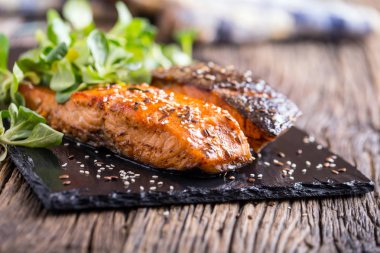 Somon fileto. Izgara somon, susam tohumu bitki decorationon vintage pan veya siyah arduvaz kurulu. Balık üzerinde eski bir ahşap masa kavrulmuş. Stüdyo vurdu