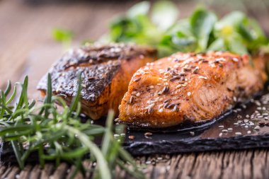 Somon fileto. Izgara somon, susam tohumu bitki decorationon vintage pan veya siyah arduvaz kurulu. Balık üzerinde eski bir ahşap masa kavrulmuş. Stüdyo vurdu