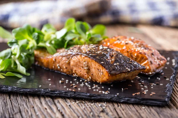 Zalmfilets. Gegrilde zalm, sesamzaad kruid decorationon op vintage pan of zwarte leisteen bord. vis geroosterd op een oude houten tafel. Studio schoot — Stockfoto