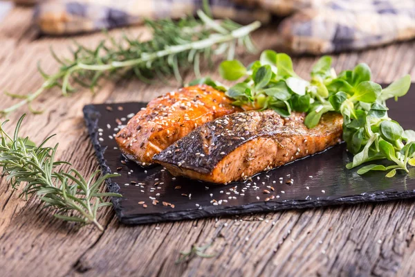 Zalmfilets. Gegrilde zalm, sesamzaad kruid decorationon op vintage pan of zwarte leisteen bord. vis geroosterd op een oude houten tafel. Studio schoot — Stockfoto