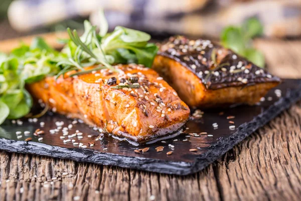 Filets de saumon. Saumon grillé, graines de sésame décoration aux herbes sur poêle vintage ou planche d'ardoise noire. poisson rôti sur une vieille table en bois. — Photo