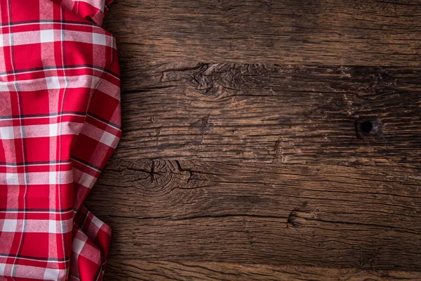 Top view of checkered tablecloth or napkin on empty wooden table — Stock Photo, Image