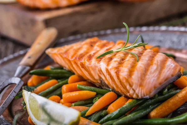 Salmon fillets. Grilled salmon, sesame seeds herb decoration on vintage pan or black slate board. fish roasted on an old wooden table.Studio shot — Stock Photo, Image