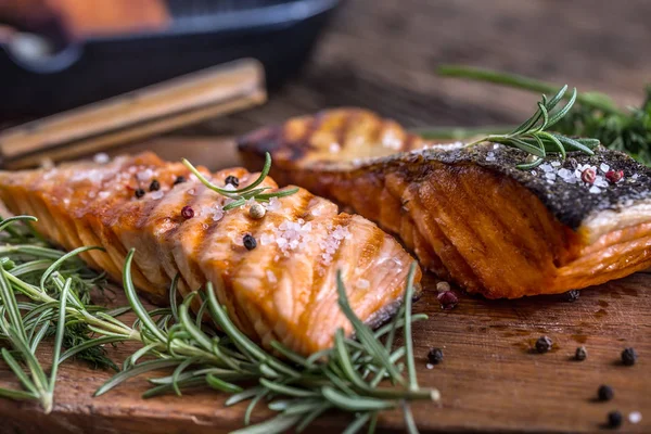 Salmon fillets. Grilled salmon, sesame seeds herb decoration on vintage pan or black slate board. fish roasted on an old wooden table.Studio shot