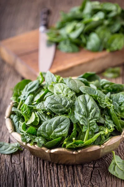 Spinach leaves.Fresh spinach leaves in retro bowl on oak wood board. Selective focus
