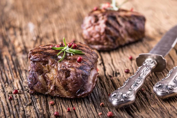 Gegrilde biefstuk met rozemarijn, zout en peper op oude snijplank. — Stockfoto