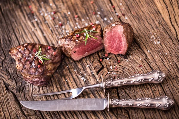 Filete de ternera a la parrilla con romero, sal y pimienta en una tabla de cortar vieja . — Foto de Stock