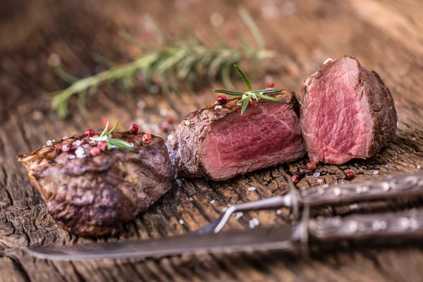 Filete de ternera a la parrilla con romero, sal y pimienta en una tabla de cortar vieja . — Foto de Stock