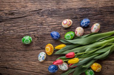 Paskalya. El yapımı Paskalya yumurtaları ve laleler eski ahşap masa üzerinde bahar