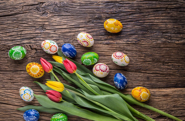 Easter. Hand made easter eggs and spring tulips on old wooden table