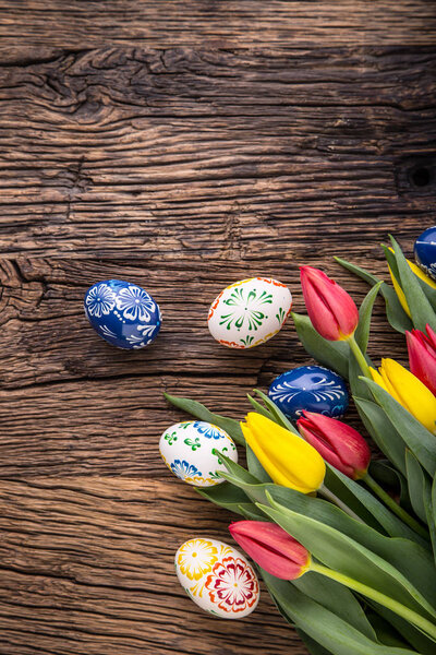 Easter. Hand made easter eggs and spring tulips on old wooden table