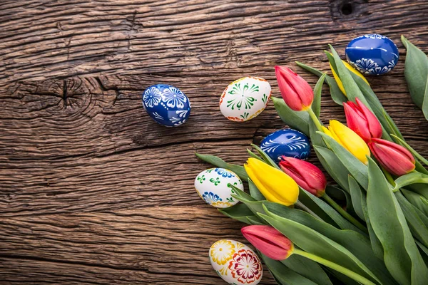 Easter. Hand made easter eggs and spring tulips on old wooden table — Stock Photo, Image