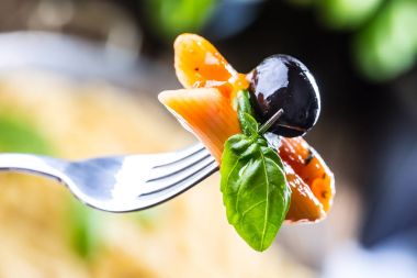 Makarna Penne domates Bolognese sos, Parmesan peyniri Siyah Zeytin ve fesleğen bir çatal üzerinde. Akdeniz yemekleri. İtalyan mutfağı