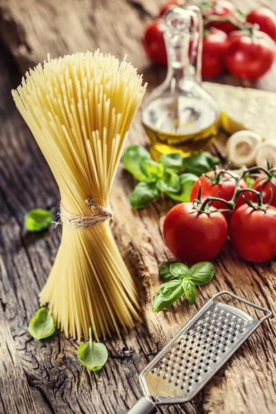 Spaghetti.Spaghetti tomates albahaca aceite de oliva queso parmesano y champiñones sobre tabla de roble muy viejo. Cocina Mediterránea e ingredientes — Foto de Stock