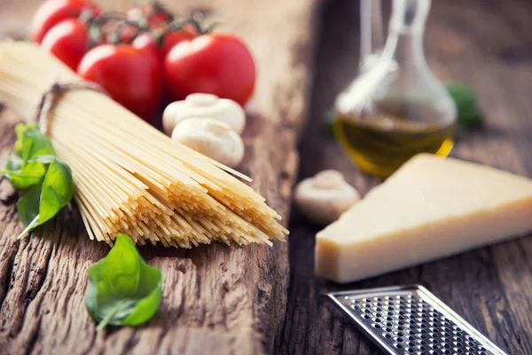 Spaghetti.Spaghetti tomatoes basil olive oil parmesan cheese and mushrooms on very old oak board. Mediterrannean cuisine and ingredients Royalty Free Stock Images