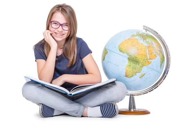 Carina piccola studentessa con globo e libro. Ragazza witrh occhiali e denti bretelle. Concetto educativo scolastico — Foto Stock