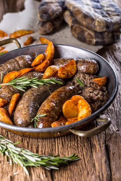 Embutidos. Salchicha de cerdo asada en una sartén con patatas y romero — Foto de Stock