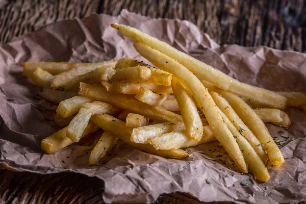 Patatine fritte. Patate fritte d'oro con sale ed erbe secche su tavola di legno — Foto Stock