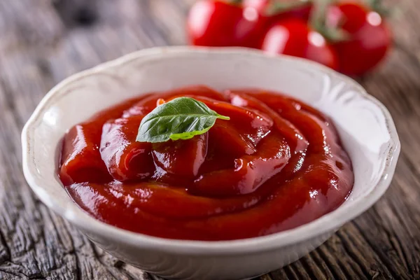 Ketchup of tomaat saus in witte kom en cherry tomaten op een houten tafel — Stockfoto